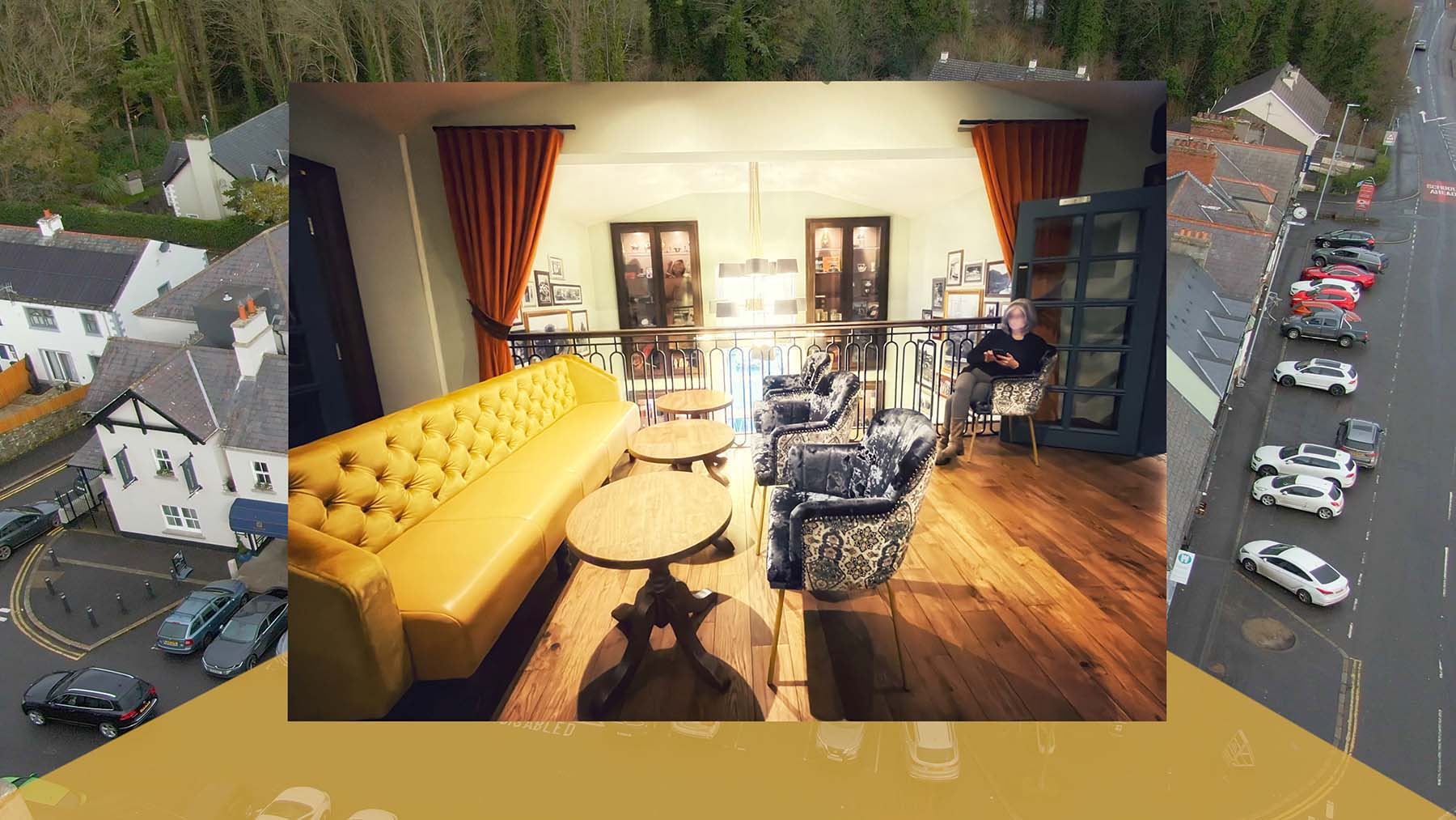 Video screenshot 6 showing photo of seating area in bar at Hillyard House overlaid on aerial footage of Castlewellan village from video by Stephen S T Bradley aerial hotel video production in the UK and Ireland